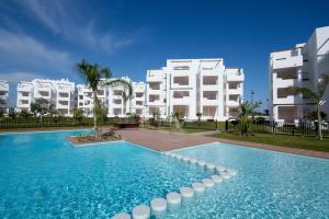 a swimming pool in front of a white building at Las Terrazas de la Torre in Las Pedreñas