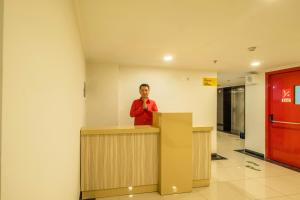 a man standing behind a counter in a room at Collection O Hotel Pasar Baru Heritage in Bandung