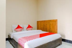 a bedroom with a bed with red and white pillows at Hotel O otel Graha Prima in Tamperan