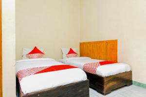 two beds in a room with red and white pillows at Hotel O otel Graha Prima in Tamperan
