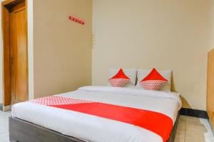 a bedroom with a bed with red and white pillows at Hotel O otel Graha Prima in Tamperan
