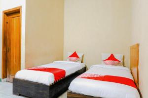 two beds sitting next to each other in a room at Hotel O otel Graha Prima in Tamperan