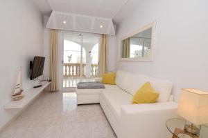 a white living room with a white couch and yellow pillows at Precioso apartamento cerca de la playa in Colonia de Sant Pere