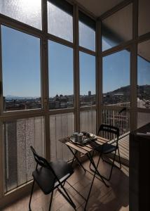 a table and chairs in a room with large windows at A cartulina e Napulè Attico con Vista Porto Ascensore Colazione Inclusa Struttura nel cuore autentico di Napoli a 5 minuti dalla Stazione Centrale e dal Centro Storico AC in Naples