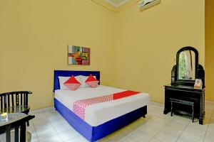 a bedroom with a bed with a mirror and a dresser at OYO 3096 Hotel Dewi Warsiki Near Gilimanuk Port in Gilimanuk