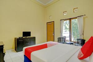 a bedroom with a bed and a tv and a window at OYO 3096 Hotel Dewi Warsiki Near Gilimanuk Port in Gilimanuk