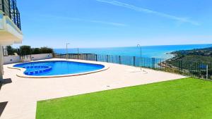 a swimming pool on the side of a house with the ocean at Ara Bela Duplex con jardin in Peniscola