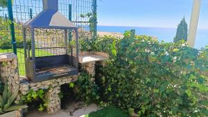 a garden with a bird cage in the bushes at Ara Bela Duplex con jardin in Peniscola