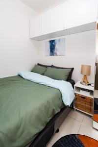 a bedroom with a bed with green sheets and a lamp at Charlie's Staycation at Coast Residences in Manila +23 photos