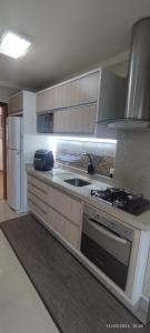 a kitchen with a stove and a refrigerator at Apartamento coração meia praia in Itapema