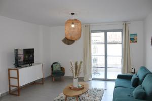 a living room with a blue couch and a tv at Les Hauts du Port-appartement élégant et central in Bonifacio