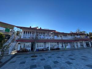 a large building with tables and chairs in a courtyard at The Whitegrove Retreat in Mukteswar