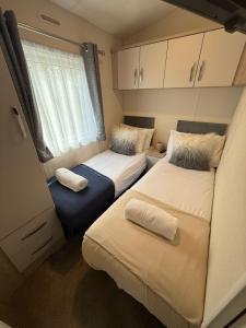 a small room with two beds and a window at Heron Lodge with Hot Tub at Brickyard Lakes in Amotherby