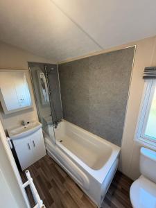 a bathroom with a tub and a sink and a toilet at Heron Lodge with Hot Tub at Brickyard Lakes in Amotherby