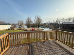 a wooden deck with a view of a river at Heron Lodge with Hot Tub at Brickyard Lakes in Amotherby