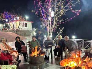 a group of people sitting around a fire at The Whitegrove Retreat in Mukteswar
