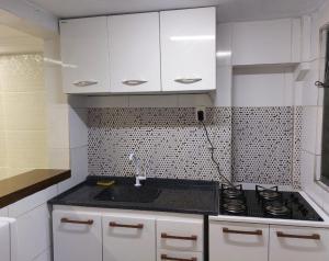 a kitchen with white cabinets and a sink and a stove at Do Alto Residencial in Curitiba