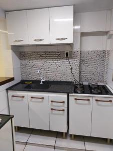 a kitchen with white cabinets and a sink at Do Alto Residencial in Curitiba +4 photos