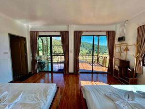 a bedroom with two beds and a balcony with sliding glass doors at Mae Klang Luang Villa แม่กลางหลวงวิลล่า in Ban Sop Mae Klang