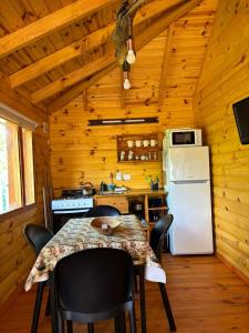 a kitchen with a table and a refrigerator at Cabañas Refugio del Cauquen - Moquehue in Moquehue +13 photos
