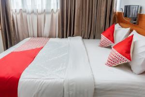 a bed with red and white pillows on it at Hotel O Mandiri Guest House Syariah in Bukittinggi +25 photos
