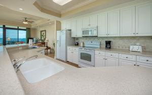 オレンジビーチにあるPhoenix West 1209 condoの白いキャビネットと大きなシンク付きのキッチンが備わります。 +44枚の写真