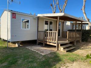 塞里尼昂Mobile home 4-6 places camping les sables du midi的一个小房子,设有门廊和凉亭