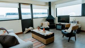 a living room with chairs and a tv and windows at Cerro Pirámide Alojamiento in Caviahue