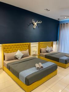 two beds in a bedroom with a blue wall at Cozy Room 5min From Airport Wi-fi & Netflix At Aeropod Sovo in Kota Kinabalu +5 photos