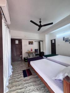 a bedroom with two beds and a ceiling fan at Hornbill inn in Cochin