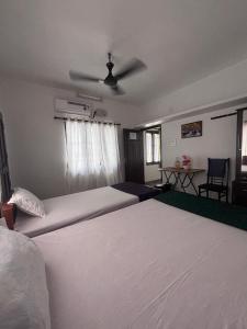 a bedroom with two beds and a ceiling fan at Hornbill inn in Cochin