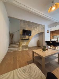 a living room with a stone wall and a table at Écrin paisible in Vergèze