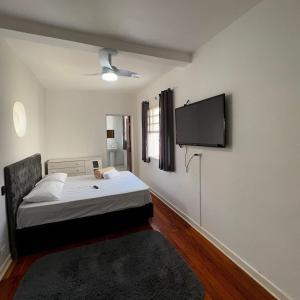 a bedroom with a bed and a flat screen tv at Pousada Madalena in Sao Paulo