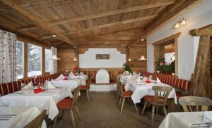 a restaurant with white tables and chairs and wooden ceilings at Hotel Rastlhof in Schenna