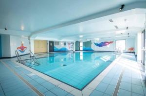 a large swimming pool with two chairs in a building at Covesea View Silver Sands in Lossiemouth