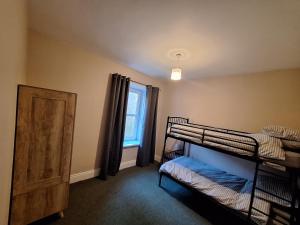 a bedroom with two bunk beds and a window at Carlcroft Cottage in Alwinton