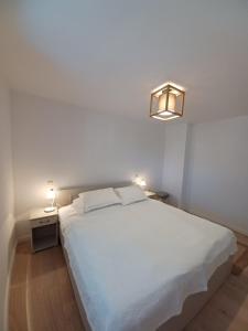 a bedroom with a large white bed and a lamp at Apartment Dry dock in Postira