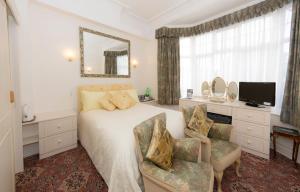 - une chambre avec un lit, un miroir et une chaise dans l'établissement Shoreline Accommodation, à Bournemouth
