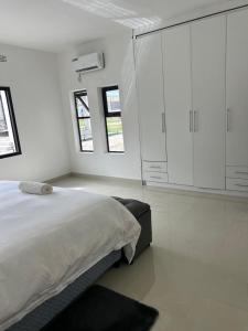 a white bedroom with a bed and some windows at Swiss Luxury Apartments - Dolla Hill in Ndola
