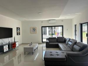 a living room with a couch and a flat screen tv at Swiss Luxury Apartments - Dolla Hill in Ndola