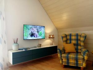 a living room with a tv and a chair at Ferienwohnungen am Waldbad Zwenkau in Zwenkau