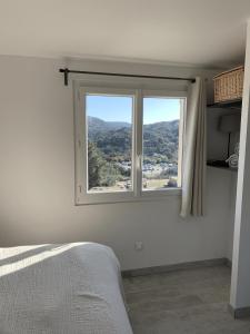a bedroom with a window with a mountain view at Charmante maisonnette proche du centre du village in La Garde-Freinet +14 photos