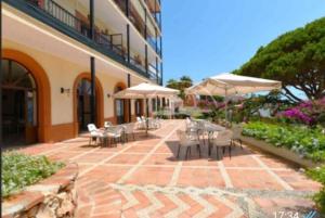 an outdoor patio with tables and chairs and umbrellas at Alhamar Cabopino Living Apartment in Málaga