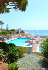 a large swimming pool with a view of the ocean at Alhamar Cabopino Living Apartment in Málaga