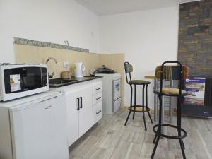 a kitchen with a microwave and two bar stools at Dorado Stey in Río Grande
