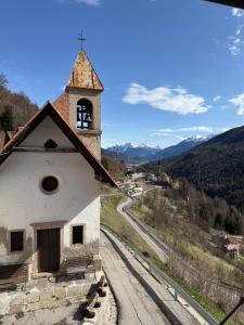a church with a clock tower on a hill at La Ciasa Dell'Emigrante in Cibiana