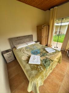 a bedroom with a bed with two books on it at Pousada Cristal de Gelo in Urubici