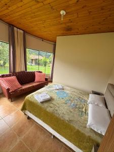 a bedroom with a bed and a couch and windows at Pousada Cristal de Gelo in Urubici