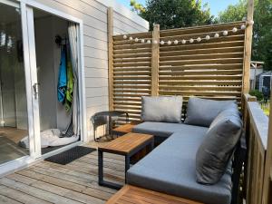 a patio with a couch and a table on a deck at Mobile home luxe au calme - 6 pers - 3 ch - 2 sdb in Camiers
