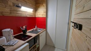 a small kitchen with a sink and a red wall at Studio spacieux - Labronie in Sarlat-la-Canéda +11 photos